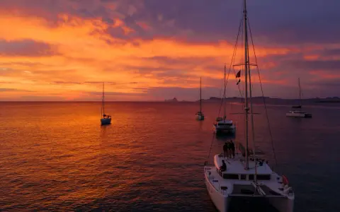 Coucher de soleil sur la mer avec des voiliers. Le tarif destruction bateau est une préoccupation pour certains, mais ici, la beauté règne.
