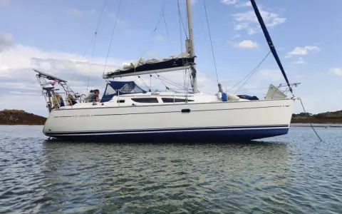 Un voilier Sun Odyssey 35, blanc avec une bande bleue, navigue paisiblement sur une mer calme. Les avis sur ce bateau sont positifs.