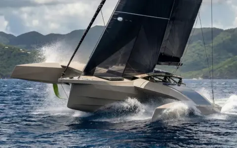Un trimaran futuriste fend les vagues, ses voiles noires déployées. Un spectacle impressionnant, digne d'un "etape 21i avis" de course.