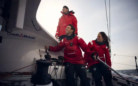 Amélie Grassi et son équipage en pleine action sur un voilier Crédit Mutuel. Le vent souffle, la mer est agitée.