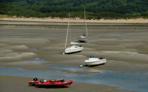Trois voiliers et un bateau à moteur échoués sur la vase, avec un zodiac rouge au premier plan. Le **kelt 9** est l'un des voiliers.