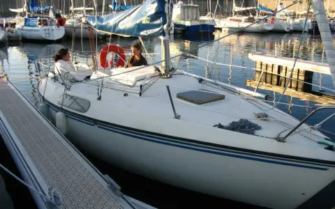 Deux personnes sur un voilier blanc, un Kelt 620, dans un port. Les avis sur ce bateau sont positifs.