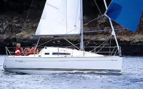 Un voilier Sun Odyssey 26 navigue sur une mer calme, avec des personnes à bord. Les avis sur ce bateau sont généralement positifs.