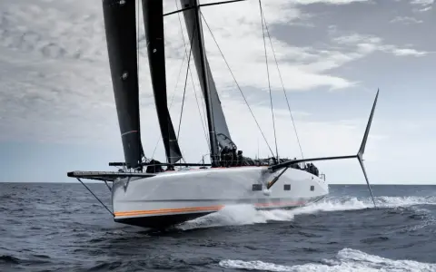 Le voilier Baltic 111 Raven fend les vagues, ses voiles noires gonflées par le vent.