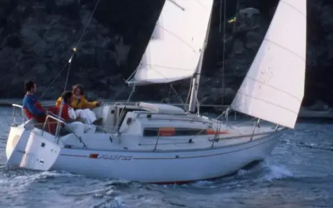 Trois personnes naviguent sur un voilier blanc, le "Pirat 26". Les voiles sont gonflées par le vent, créant une scène paisible.