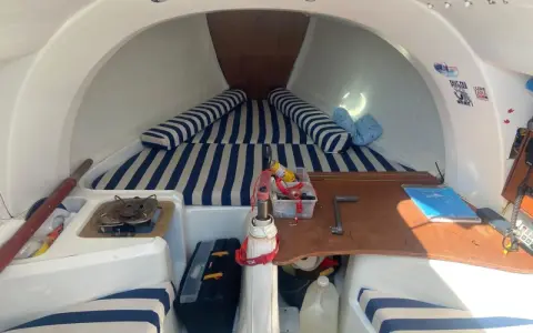 Intérieur du first 210, avec banquettes rayées bleu et blanc, réchaud, outils et bidon d'eau. Prêt pour l'aventure !