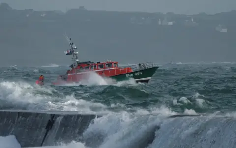 Bateau de sauvetage SNS 068 naviguant dans une mer agitée, affrontant la tempête. Les vagues déferlent sur la proue.