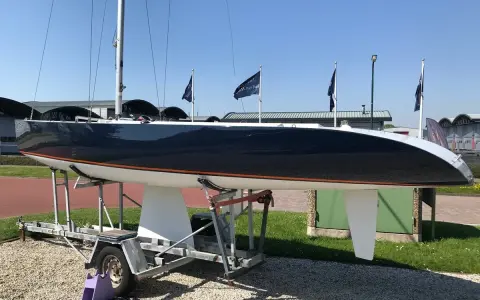 Voilier de course noir et blanc, un modèleBepox 750, sur sa remorque, prêt pour l'aventure.