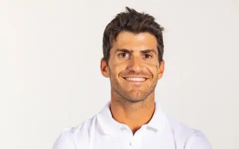 Portrait souriant de Kévin Peponnet, athlète français en polo blanc, sur fond clair.