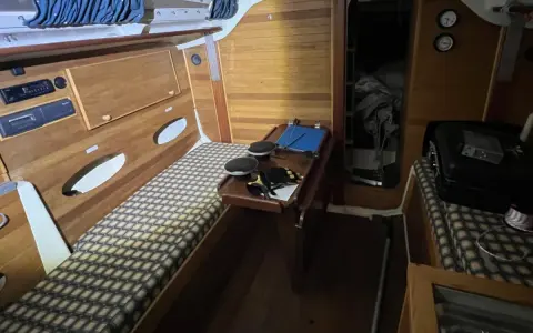 Intérieur d'un voilier Trident 80. Banquette, table pliante, rangement et couchette.