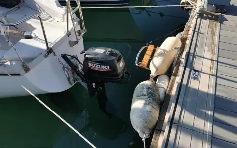 Un voilier "love love" amarré au ponton, avec un moteur Suzuki prêt à l'action. Des pare-battages protègent la coque.