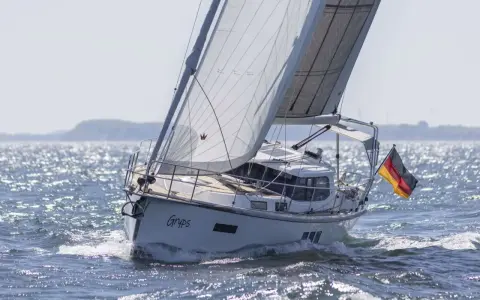 Le voilier Sirius 40 DS "Gryps" navigue sur une mer scintillante, pavillon allemand au vent.