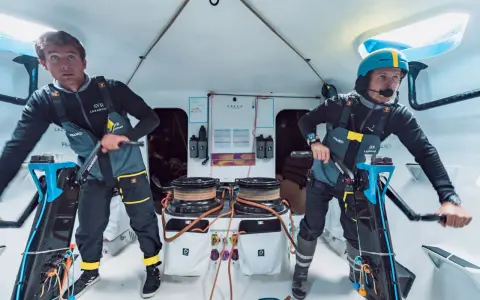Deux marins concentrés sur le pont d'un bateau, prêts pour la course **Kerkena 6.1**.