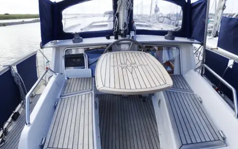 Cockpit d'un Nauticat 33 avec table en teck ornée d'une rose des vents. Détails techniques visibles.