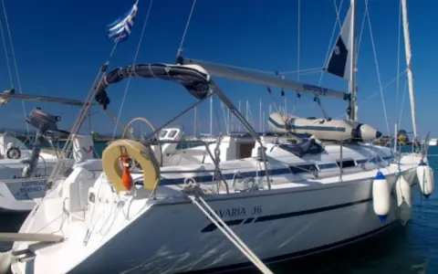 Voilier Bavaria 36 blanc amarré, pavillon grec, pare-battages bleus et blancs.