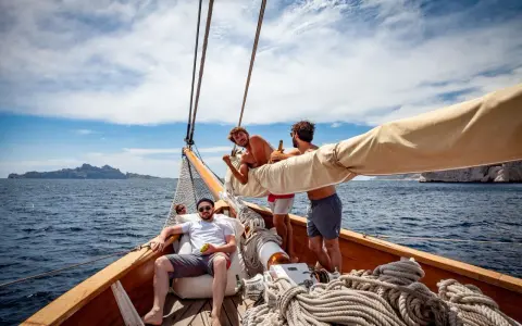 Trois amis profitent du soleil sur un voilier, rêvant d'un tour du monde. L'eau bleue et les falaises en arrière-plan ajoutent à l'aventure.