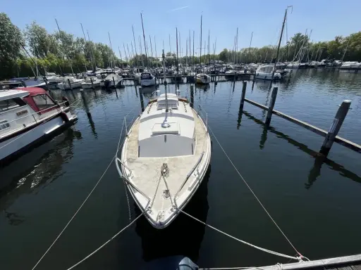Un voilier blanc, type Westerly Centaur, est amarré dans un port. D'autres bateaux sont visibles au loin.