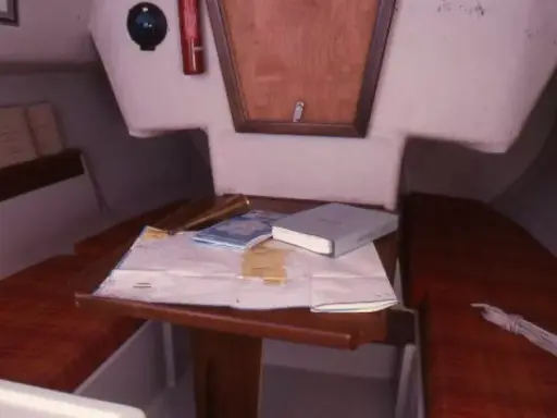 Vue du premier 22 intérieur d'un voilier, avec une carte marine, des livres et un compas.