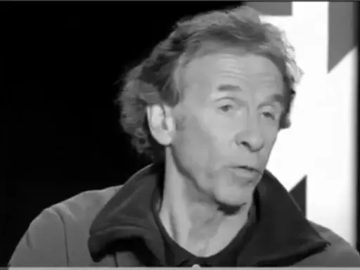 Portrait en noir et blanc d'Éric Loizeau, homme aux cheveux ondulés, parlant dans un micro.