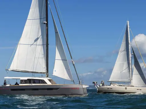 Deux grands voiliers naviguent sur une mer bleue sous un ciel clair.