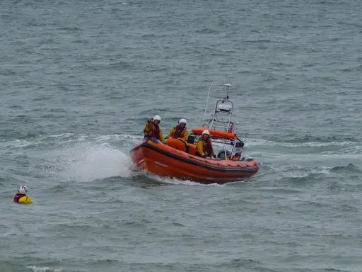 Bateau de sauvetage orange avec équipage en action. Une personne dans l'eau, une fusée de détresse bateau obligatoire est essentielle.