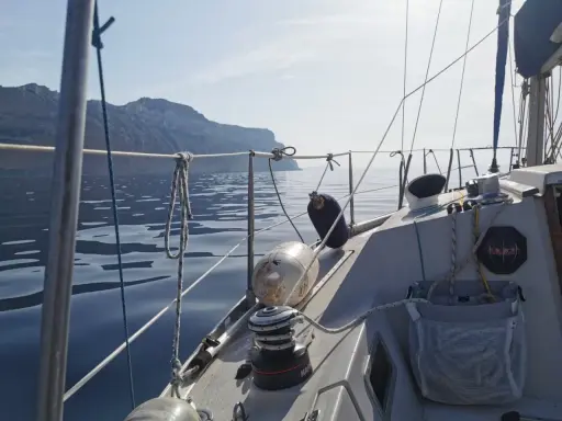 Vue depuis un voilier Aquila, naviguant sur une mer calme avec des falaises en arrière-plan. Avis de navigation paisible.