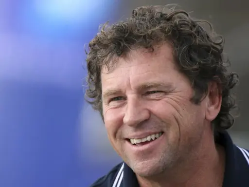 Lionel Lemonchois, skipper souriant, cheveux bouclés, sur fond bleu.