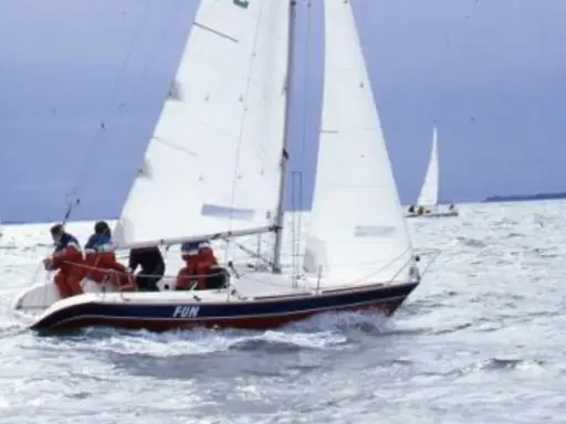 Un voilier nommé "FUN" navigue sur une mer agitée, avec des personnes à bord profitant de la navigation.