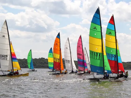 Course de Hobie Cat 18, voiles multicolores et blanches, sur l'eau par temps nuageux. Fiche technique du Hobie Cat 18.