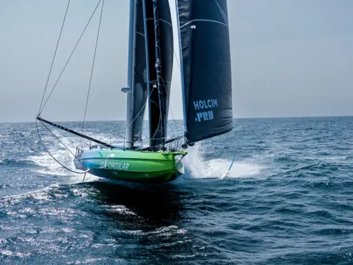 Voilier vert et bleu "Go Circular" naviguant à pleine vitesse, voiles noires marquées "Holcim PRB". Un design de Guillaume Verdier.