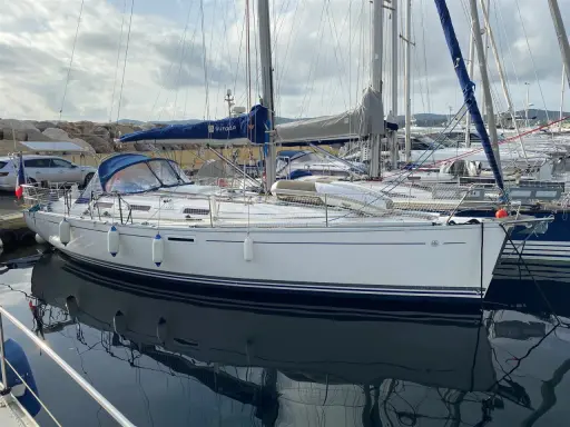Un voilier Dufour 385 Grand Large blanc, amarré dans un port, reflète son élégance sur l'eau calme.
