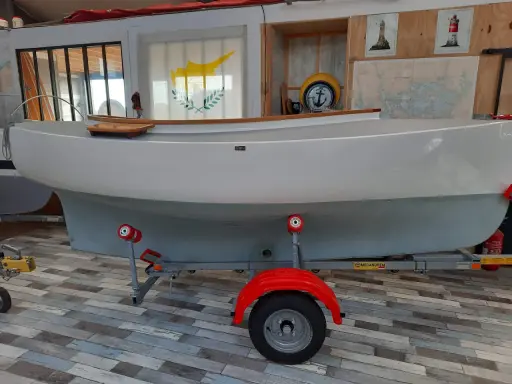 Bateau blanc sur remorque, prêt pour l'aventure. Le drapeau chypriote flotte, rappelant les eaux bleues. Un **pabouk 360** attend son prochain voyage.