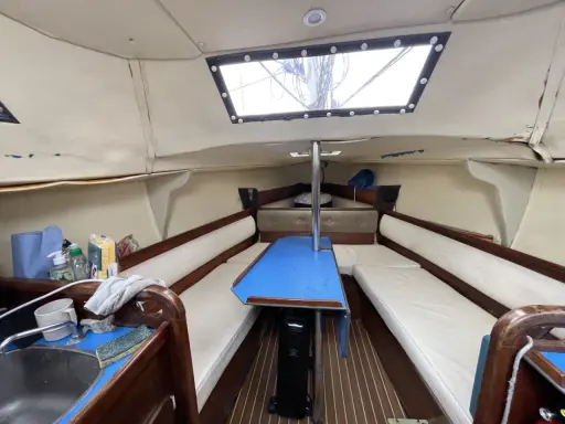 Intérieur d'un voilier, avec banquettes, table bleue et évier. Un coin de fantasia voilier interieur prêt pour l'aventure.