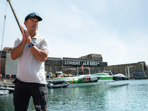 Un homme applaudit devant le trimaran Sodebo Ultim 4, prêt à naviguer.