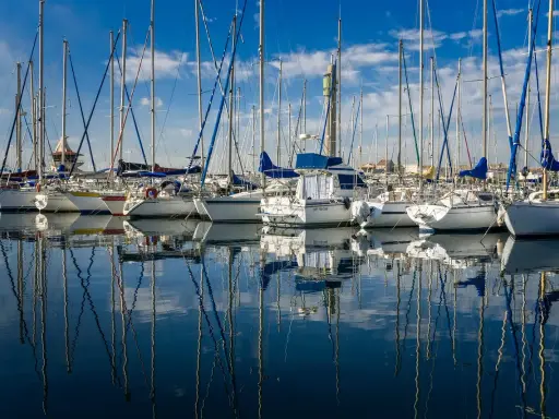 Une flotte de voiliers blancs, reflets parfaits sur l'eau calme. Un chantier naval, le constructeur bateau, a créé ces merveilles.