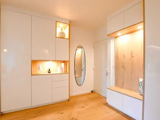 Ambiance chaleureuse dans cet intérieur de Kelt 550, avec des rangements blancs laqués et des niches en bois illuminées. Un miroir ovale ajoute une touche d'élégance.