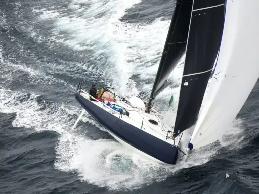 Un voilier de course fend les vagues, ses voiles noires et blanches gonflées par le vent. On dirait qu'il nous montre comment naissent les bateaux, prêts à conquérir l'océan.