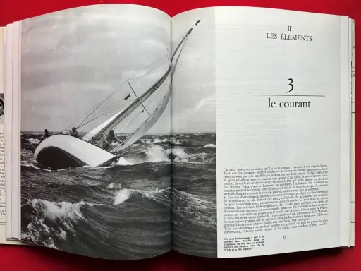 Un voilier navigue dans une mer agitée, ses voiles gonflées par le vent. Alain Gliksman, passionné de voile, admire cette scène.