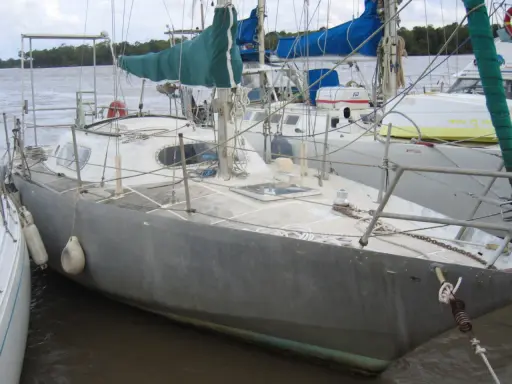 Voilier gris amarré, prêt pour une brise de mer 31. Voiles vertes et bleues, cordages et bouées.