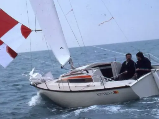 Deux hommes naviguent sur un voilier blanc, le "Esterel", avec des voiles rouges et blanches. Les premiers 22 avis sur ce bateau sont probablement très positifs.