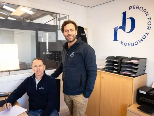 Dimitri Caudrelier et son collègue dans leur bureau, avec le logo "Reborn for Tomorrow" au mur.