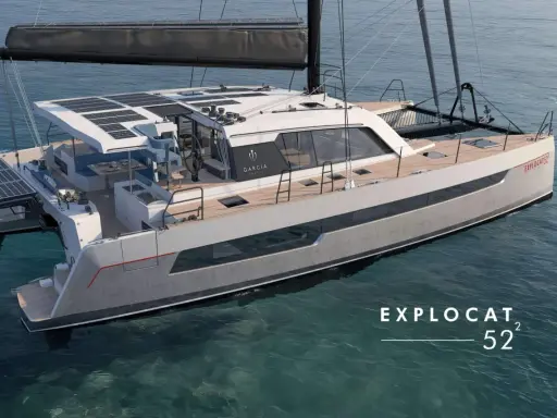 Un catamaran de luxe, un **deriveur integral** moderne, navigue sur des eaux bleues claires. Panneaux solaires sur le toit, design épuré.