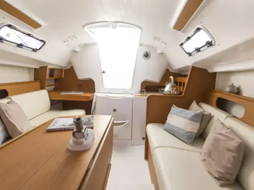 L'intérieur d'un voilier moderne, avec des banquettes en cuir, une table en bois et des hublots. Le premier 25 interieur est lumineux et spacieux.