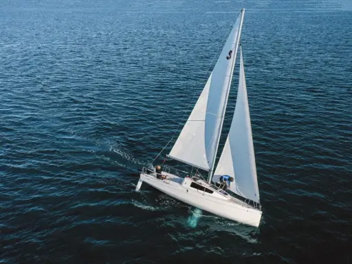 Un voilier blanc navigue sur une mer bleue. Sa quille est visible sous l'eau, stabilisant le bateau.