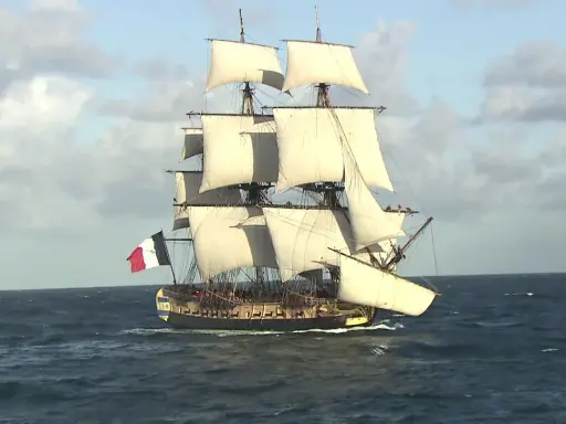 La frégate Hermione, fierté de la marine française, navigue majestueusement sur l'océan, ses voiles gonflées par le vent.