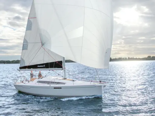 Voilier Dehler 34 naviguant par temps calme. Les voiles blanches sont gonflées, deux personnes sont à la barre. Fiche technique du bateau.