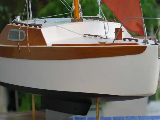 Modèle de voilier corsaire, coque blanche et bois verni, voile orange. Fiche technique détaillée.