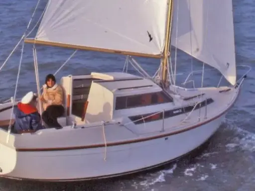 Un voilier Evasion 22 navigue sur une mer agitée, deux personnes à bord profitent de la brise.