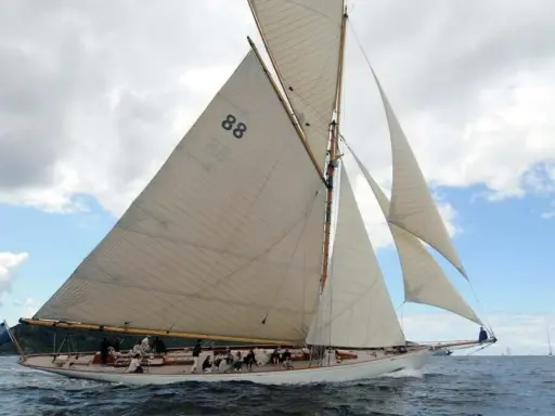 Le voilier "Moonbeam 4" navigue sur une mer agitée, ses voiles blanches gonflées par le vent.