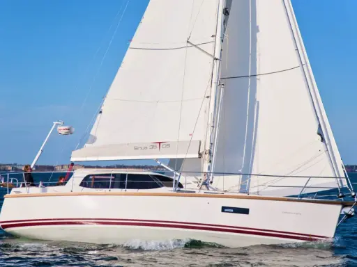 Voilier blanc Sirius 35 DS naviguant sur une mer bleue, avec le drapeau allemand à l'avant.